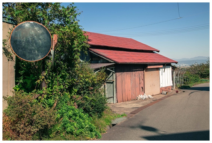 赤い屋根の納屋と遠くに見える会津盆地