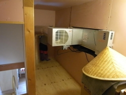 集熱した熱い空気を床下に送り込む小屋裏のファンとダクト