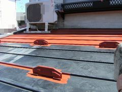 トタン屋根に錆び止め塗料を塗っている。赤いものが錆び止め